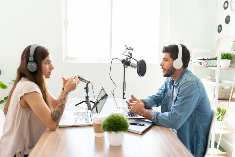 Two people opposite talking into microphones
